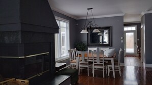 Un comedor con chimenea, sillas blancas y una mesa.