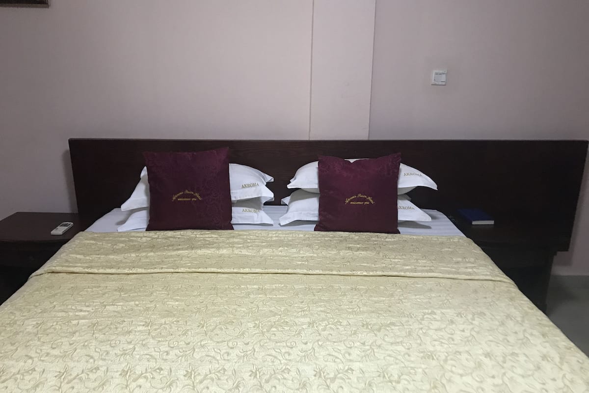 A hotel room with a bed, two pillows, a bedside table, and a nightstand.
