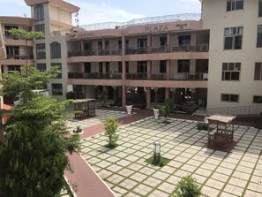 Un edificio de varios pisos con balcones, un patio central con asientos y un letrero que dice "PLAZA".