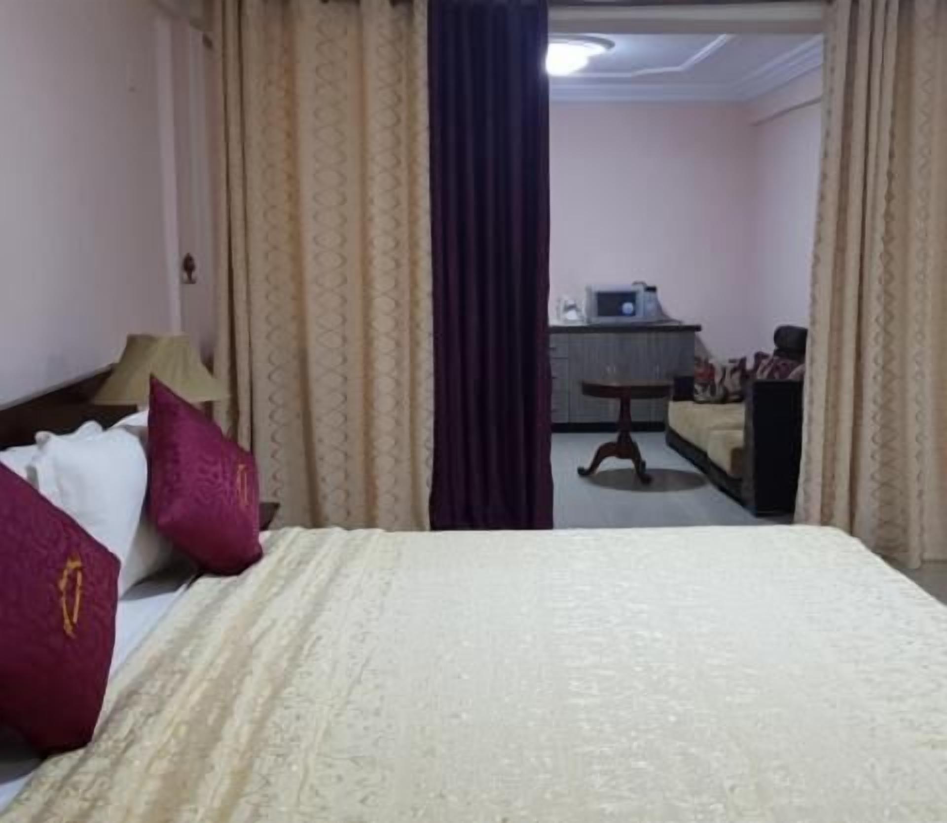 Ein Hotelzimmer mit Bett, Schreibtisch, Stuhl, einem kleinen Tisch und einer Küchenzeile.