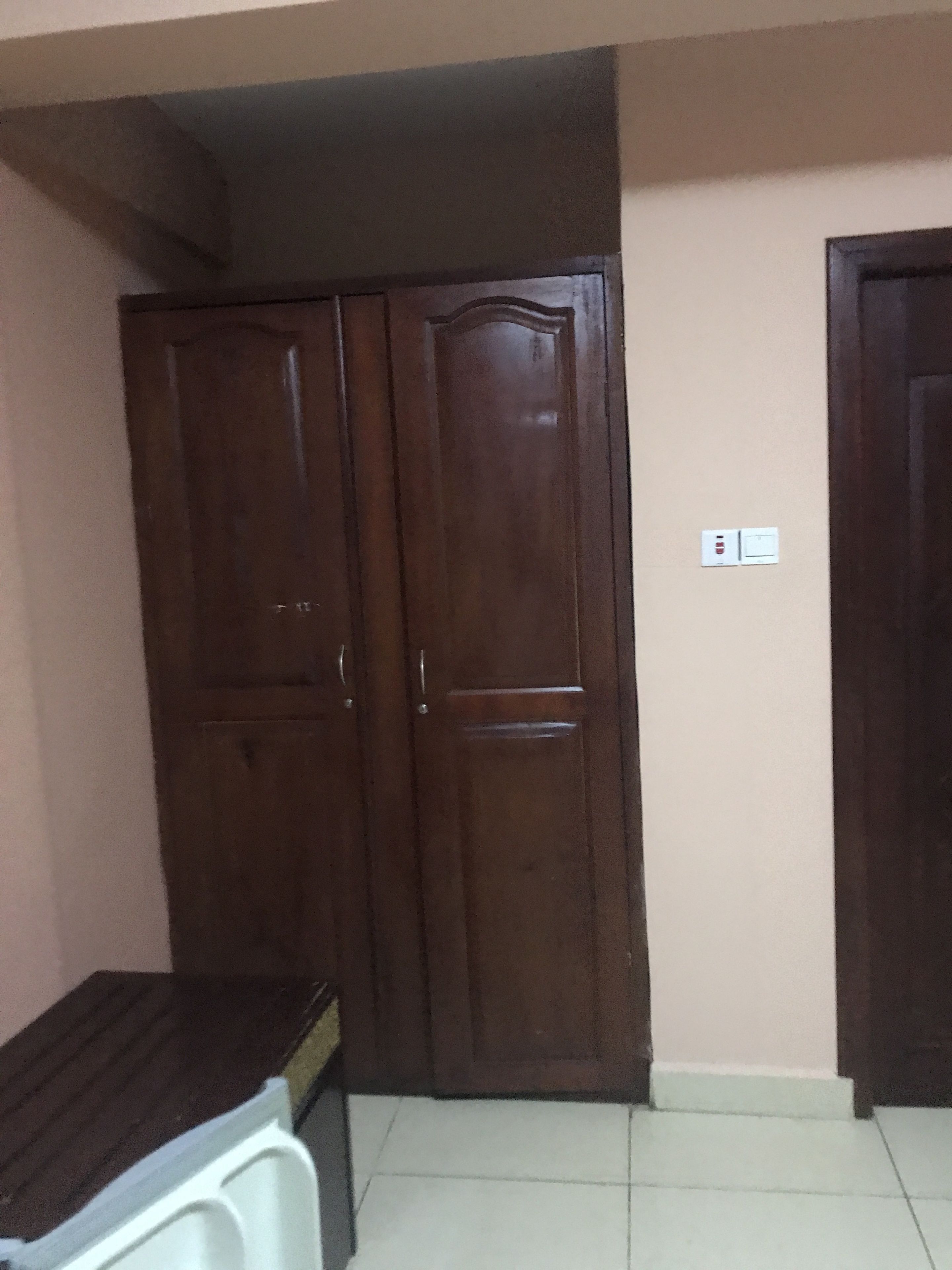 A room with two wooden wardrobes, a white washing machine, and a tiled floor.