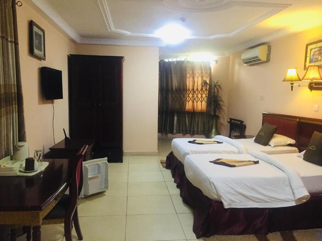 Habitación de hotel con dos camas, un escritorio, una silla, un televisor y una ventana con cortinas.