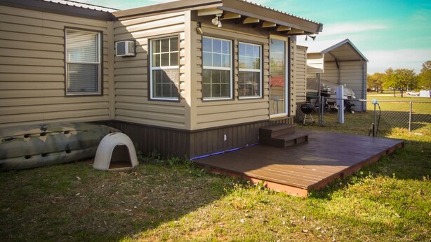 Een klein, gelijkvloers huis met een veranda, een overdekt terras en een omheinde tuin.