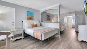 Ein Schlafzimmer mit Bett, Nachttisch, Kommode und einem Bild einer Strandlandschaft.