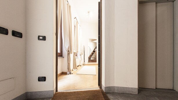 A hotel hallway with a brown doormat, a light-colored carpet, and a wooden floor. - Hemeras Boutique House Aparthotel Duomo 6 (Milan)