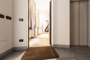 A hotel hallway with a brown doormat, a light-colored carpet, and a wooden floor.
