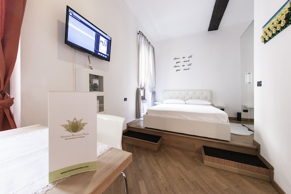 A hotel room with a bed, a desk, a television, and a wall with a motivational quote.
