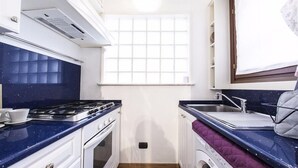 A compact kitchen with a stove, sink, and a window above the sink. - Hemeras Boutique House Aparthotel Duomo 6 (Milan)