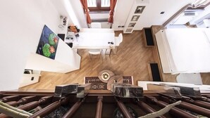 A modern hotel room with a wooden floor, a dining area with a white table and chairs, and a large painting on the wall. - Hemeras Boutique House Aparthotel Duomo 6 (Milan)