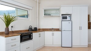 A modern kitchen with white cabinets, a granite countertop, a built-in microwave, a refrigerator, and a window with a view of the city. - Harbour Lights 306 - Adults Only (Cape Town)