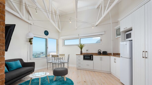 A modern kitchen with white cabinets, a black oven, and a white refrigerator. - Harbour Lights 306 - Adults Only (Cape Town)