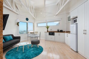 Une cuisine moderne avec des meubles blancs, un four noir et un réfrigérateur blanc.