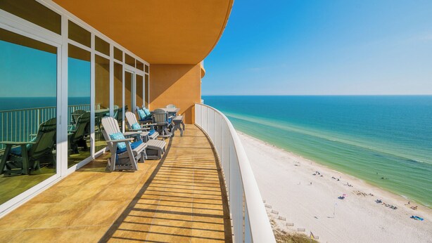 Een balkon met zitplaatsen met uitzicht op een strand.