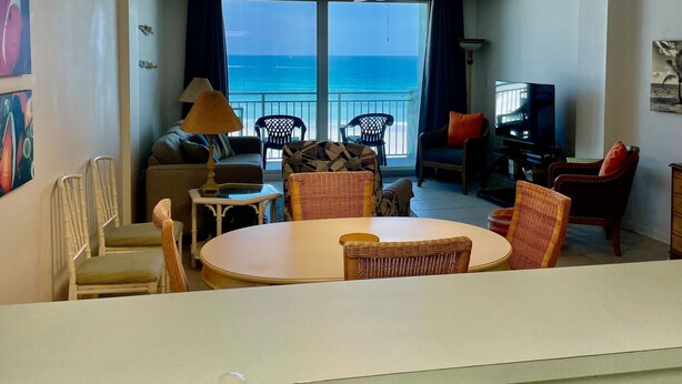 Habitación de hotel con balcón, zona de comedor y televisor.