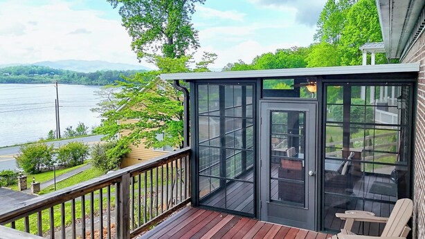 A wooden deck with a glass door leading to a patio area with outdoor furniture. - Lake Chatuge Bungalow by Chatuge Home Concierge | Cozy Pet-Friendly Retreat · Lake & Mountain Views · Firepit (Hiawassee)