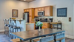 A modern kitchen with wooden cabinets, stainless steel appliances, and a central island with seating. - Lake Chatuge Bungalow by Chatuge Home Concierge | Cozy Pet-Friendly Retreat · Lake & Mountain Views · Firepit (Hiawassee)