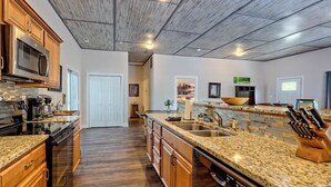 A spacious kitchen with granite countertops, wooden cabinets, and a stainless steel range hood. - Lake Chatuge Bungalow by Chatuge Home Concierge | Cozy Pet-Friendly Retreat · Lake & Mountain Views · Firepit (Hiawassee)