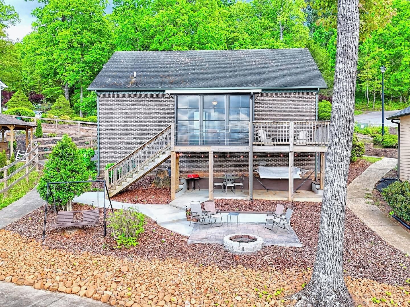 A modern house with a brick exterior, a covered patio with outdoor seating, and a fire pit.