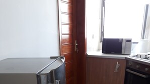 Une cuisine équipée d’un réfrigérateur en acier inoxydable, de meubles de rangement en bois, d’un four à micro-ondes et d’un four traditionnel.