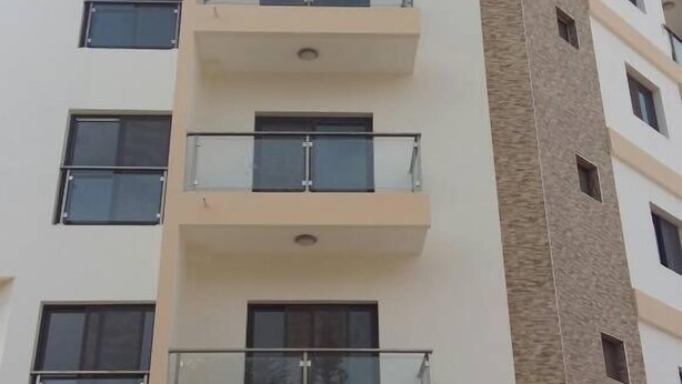 Un immeuble à plusieurs étages doté de balcons, d’une façade plane et d’une variété de styles de fenêtres.