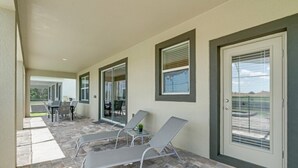 Un patio cubierto con dos sillones, una mesita y una puerta con ventanal.