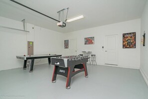 A room with two foosball tables, a projector, and a door.