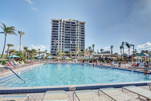 Relax by the pool, surrounded by lounge chairs and umbrellas.