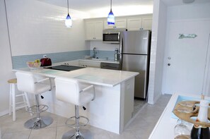 Enjoy cooking in this well-equipped kitchen with a central island, stainless steel appliances, and a herringbone tile backsplash.