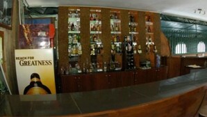 Un espace bar avec un comptoir en bois et une affiche sur laquelle on peut lire : « ASPIRER À L’EXCELLENCE ».