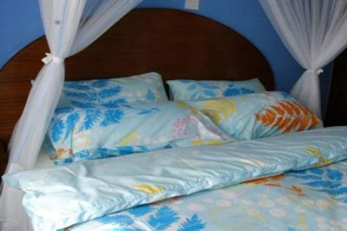 Una cama con dosel, ropa de cama floral y cabecero de madera.