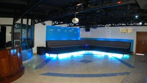 Une pièce dotée d’un espace salon aux lignes courbes, d’un comptoir de bar et d’une boule à facettes.