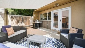 An outdoor patio area with wicker furniture, a grill, and a patterned rug.