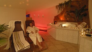 A spa room with a reclining chair, a bathtub, and a wall-mounted massage table. - Landhotel zur Post (Schoenheide)