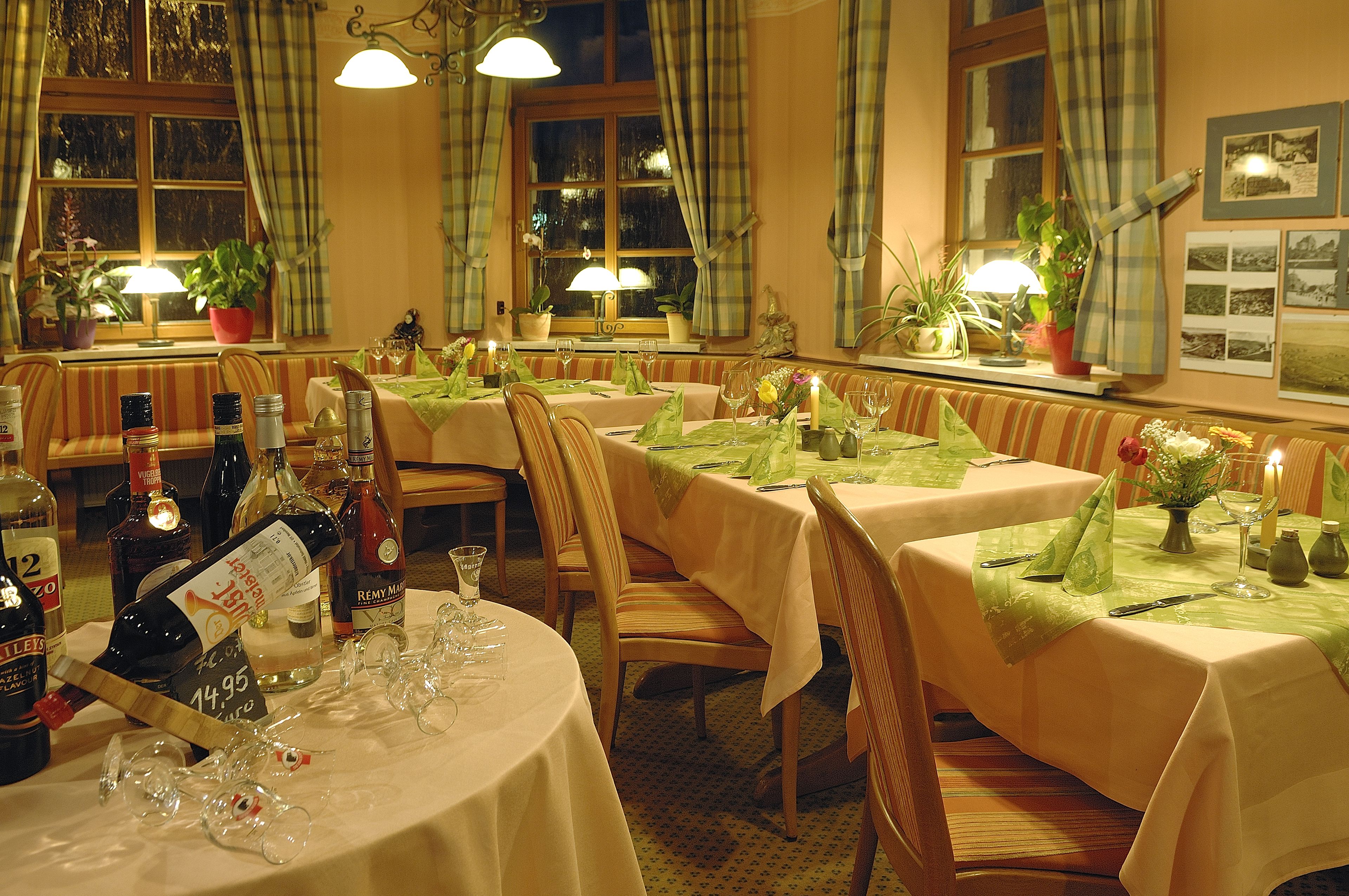 A restaurant with multiple tables set for dining, each with a tablecloth, chairs, and table settings.
