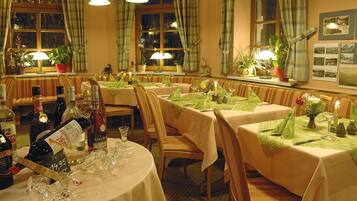 A restaurant with multiple tables set for dining, each with a tablecloth, chairs, and table settings.