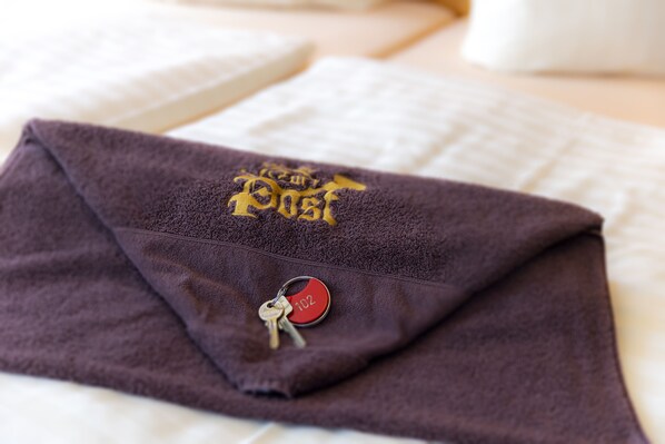 A purple towel with a logo and a keychain on a bed.
