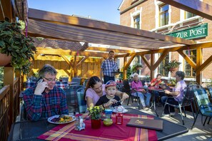 An outdoor patio area with wooden pergola, metal tables, and chairs. - Landhotel zur Post (Schoenheide)