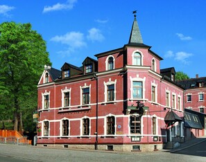 A red brick building with a prominent tower and a clock. - Landhotel zur Post (Schoenheide)