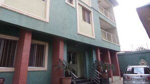 A multi-story building with a green facade, red brick columns, and a balcony on the second floor. - Terris Hotel and Suites (Lagos)