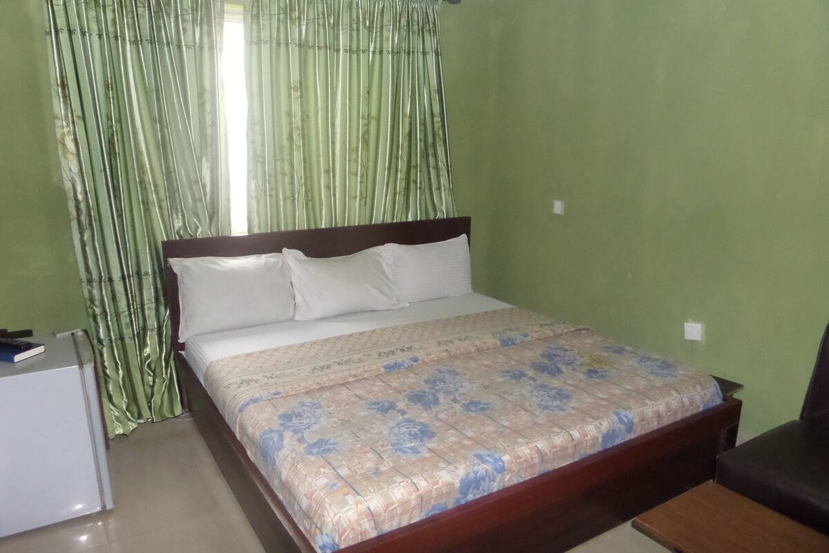 A bedroom with a bed, a nightstand, and a desk.