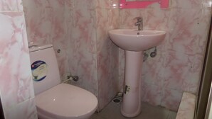 A bathroom with a pink toilet, a pedestal sink, and a mirror with a pink frame. - Terris Hotel and Suites (Lagos)