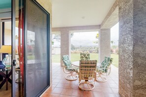 Relax in this open-plan living area with a patio offering a view of the well-maintained lawn and distant hills.