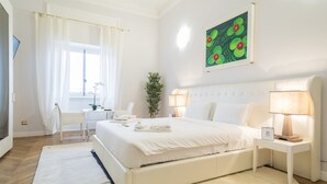 Ein Hotelzimmer mit Bett, Nachttischen, einem Schreibtisch und einem Fenster mit Vorhängen.