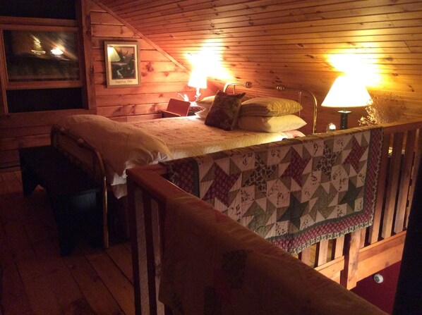 A cozy cabin room with a bed, a chair, and a wooden ceiling. - Perry Pond Paradise! (Narrowsburg)