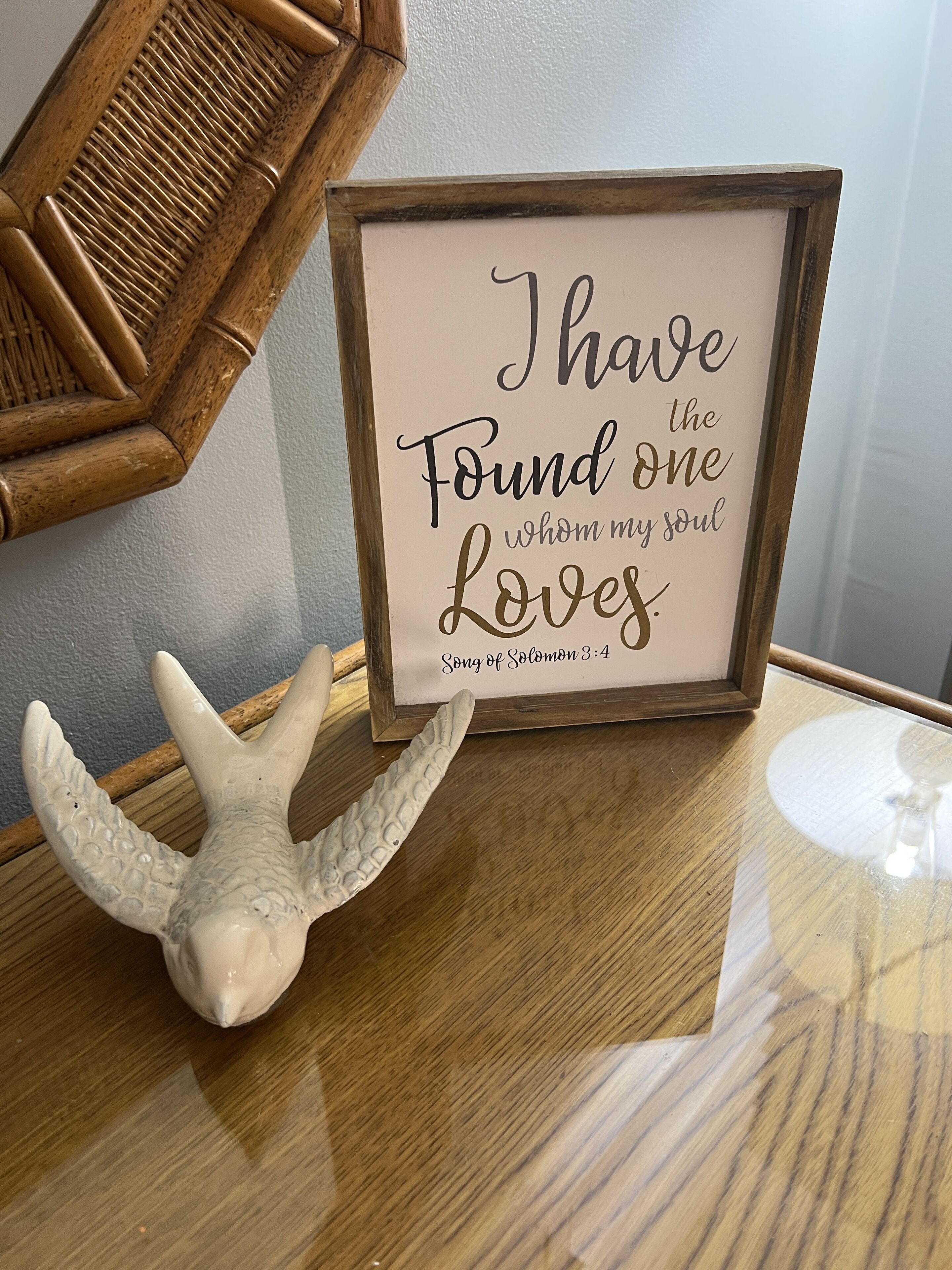 Ein gerahmter, inspirierender Spruch auf einem Holztisch, zusammen mit einer dekorativen Muschel.