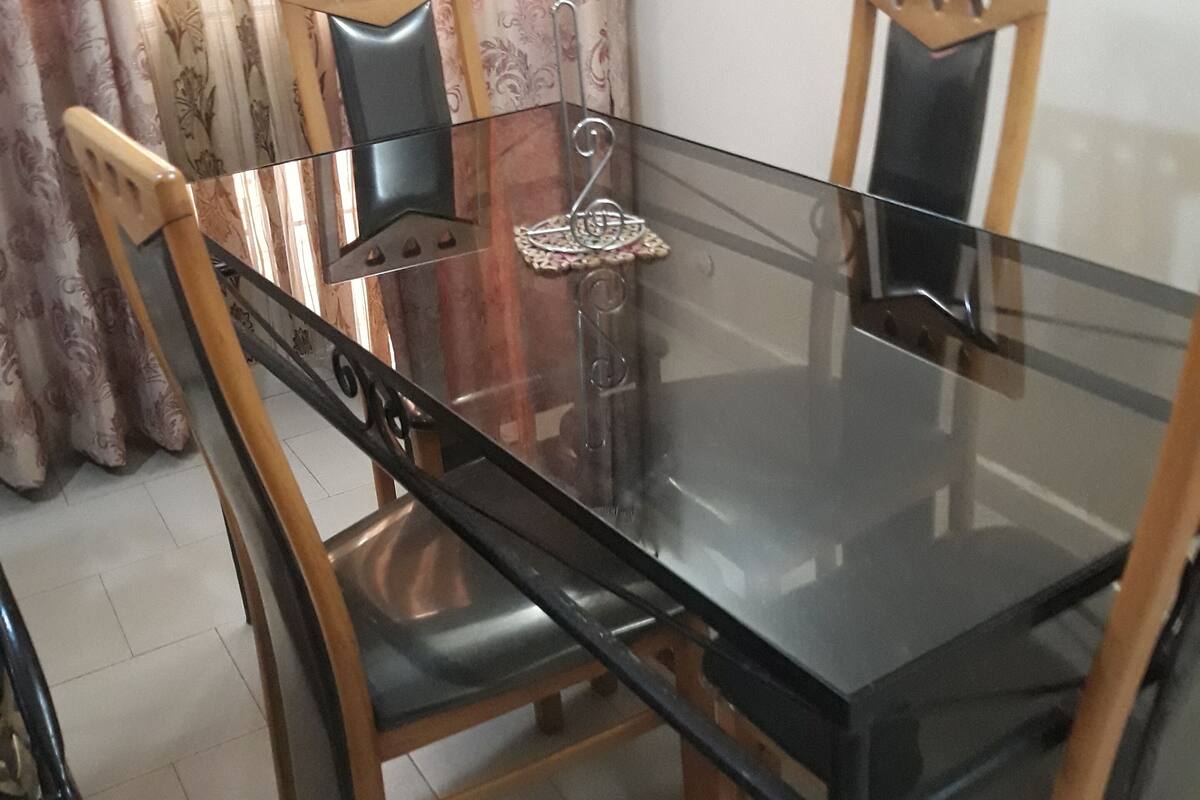 A dining table with chairs, a decorative item, and curtains.