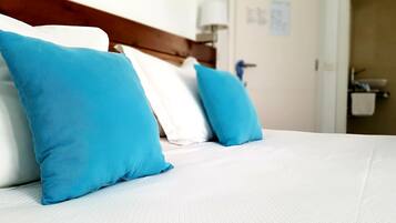A neatly made bed with white bedding and two bright blue pillows.