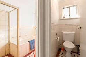 Un baño con bañera, inodoro y ventana.