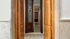Un pasillo con marco de puerta de madera, piso estampado y pared con azulejos.