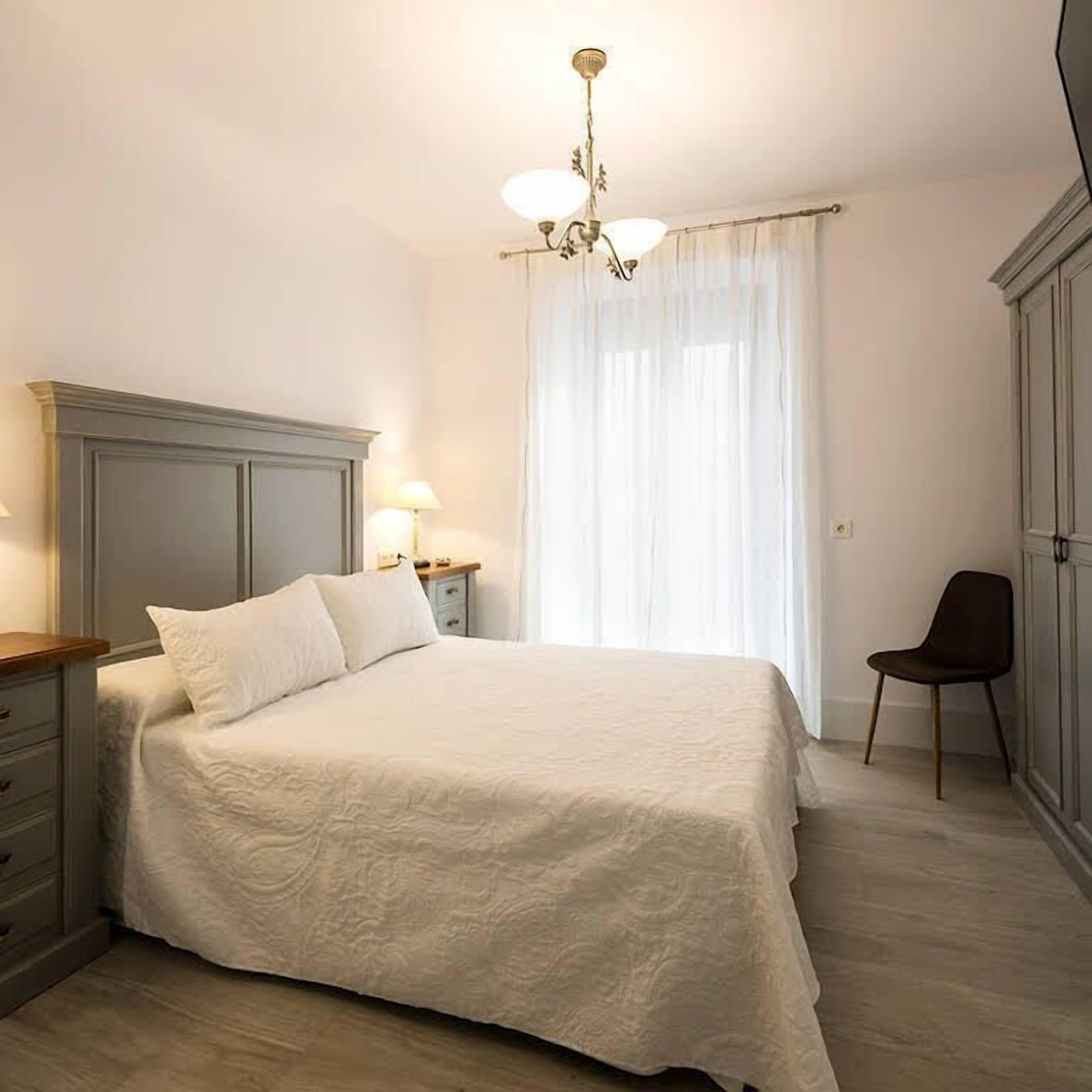 A bedroom with a bed, a nightstand, a chair, and a wardrobe.